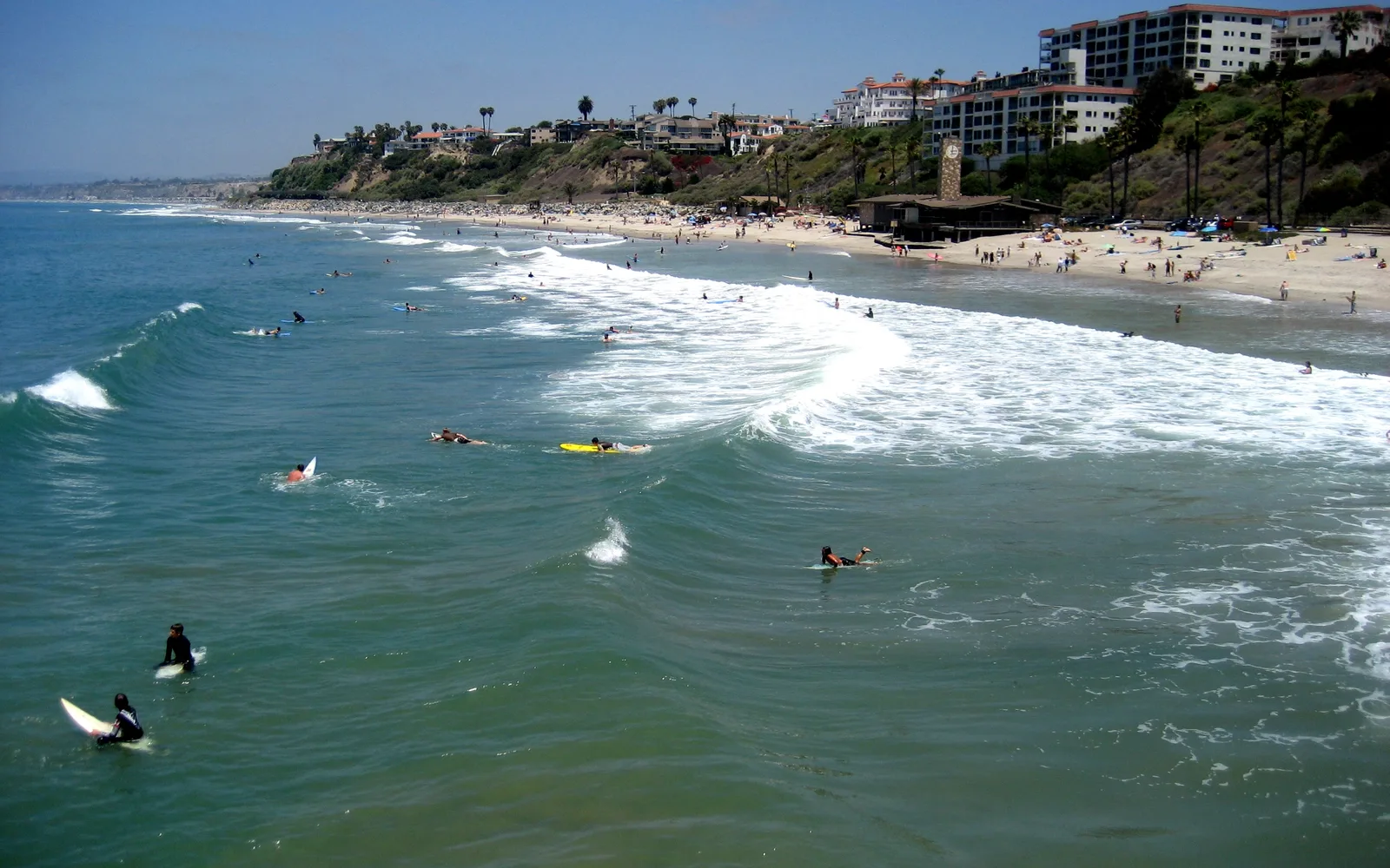San Clemente Pier extending into the Pacific Ocean with surfers and swimmers visible in the water